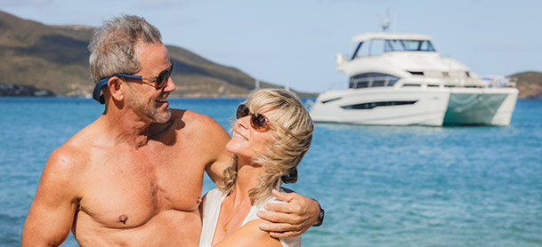 Couple hugging with a MarineMax vacations power catamaran in the background
