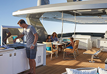 man grilling for family on deck of yacht