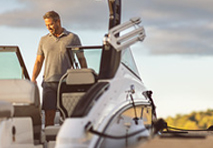 a man in a polo shirt stands on a sleek white boat smiling warmly