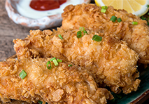a plate of crispy fried chicken pieces garnished with herbs served on a white dish