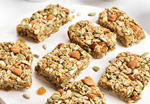 granola bars topped with a variety of nuts and seeds arranged neatly on a wooden surface