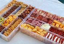 a plastic container filled with a variety of snacks including chips nuts and pretzels arranged on a tray