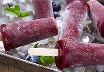 a tray of colorful popsicles topped with fresh blueberries arranged neatly for a refreshing summer treat