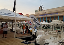 people walking under a white marinemax tent on a dock and looking at the boats in the water in front of the tampa convention center