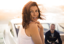 woman in front of yacht peers quizzically over her shoulder