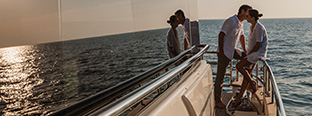 Couple standing together leaning against railing of yacht