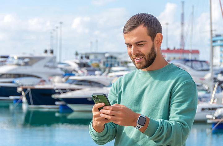 man looking at a phone at a marina