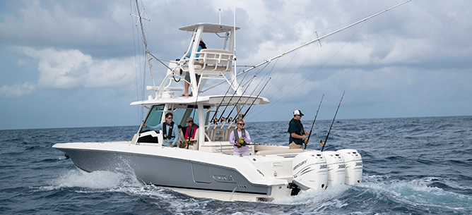 White and grey Boston Whaler fishing boat in the water with people fishing off of it