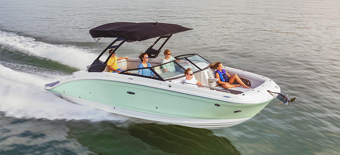 A green and white Sea Ray SDX 270 races across the water with people aboard