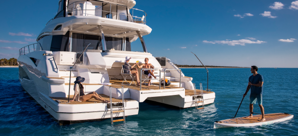 Aquila power catamaran with a paddleboarder next to it