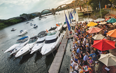 Crowd watches yachts travel down river