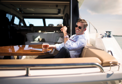 Man seated on yacht enjoys a cigar
