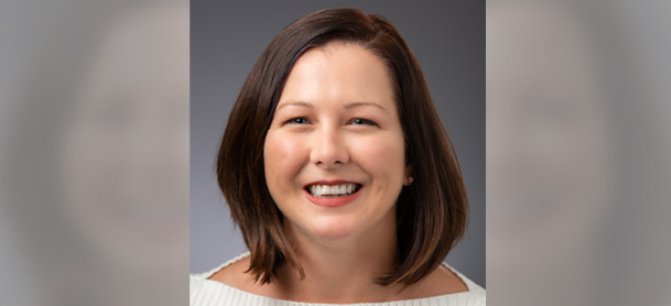 Amanda Ward smiling with shoulder-length brown hair against a gray background. She's wearing a light-colored top, conveying a friendly, approachable tone.