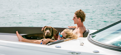 Couple enjoying the sun on yacht with their brown labrador
