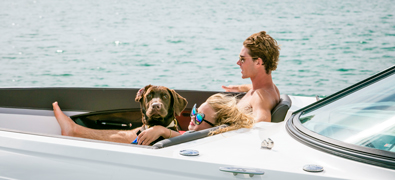 couple enjoying the sun on yacht with their brown labrador