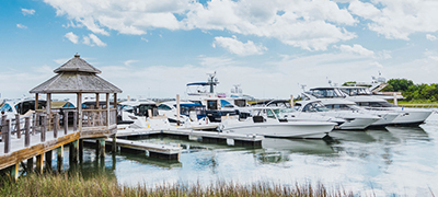 boats lined up along a dock in calm waters with a gazebo