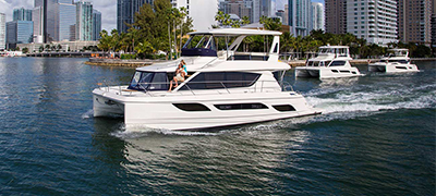 Aquila running on smooth intracoastal with two other Aquila boats behind it and skyscrapers in the background