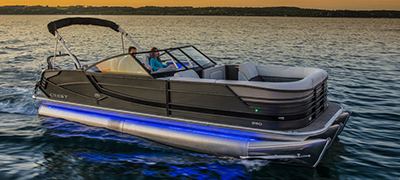 sunset or evening with a crest pontoon still in calm dark waters with glowing blue or purple accent lights on the boat