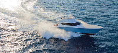 white hatteras yacht slightly turning on dark choppy waters with the late afternoon sun glistening off the wake