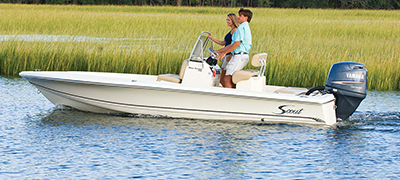 open scout with two people on board running through reeds on a lake