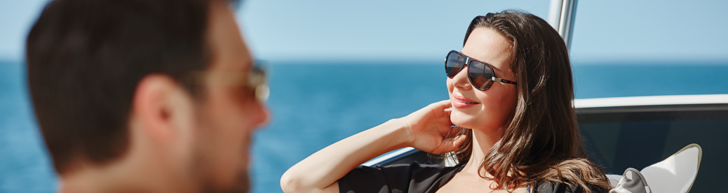 smiling woman on yacht running fingers through hair while taking in the beautiful ocean scenery