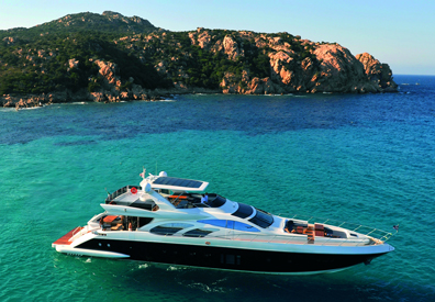 beautiful large yacht anchored in clear blue waters next to rocky island 