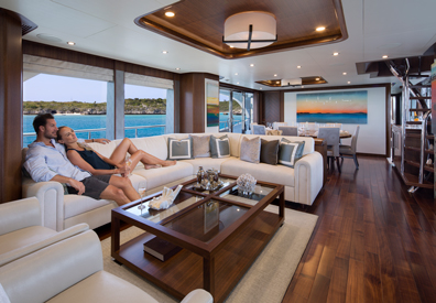 couple lounging on spacious white leather sofa taking in the luxurious interior furnishing of yacht