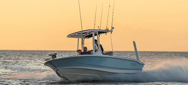 A small, sleek motorboat speeds across the water at sunset.