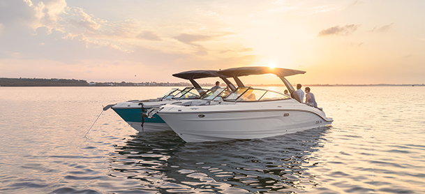 Two white boats float on calm water at sunset, casting gentle reflections.