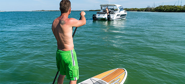 man on stand up paddle board in front of boat