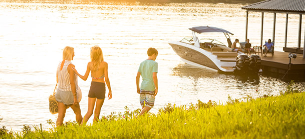 family walking along the shoreline towards a boat on a dock
