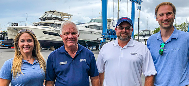 three men and a woman standing in front of a boat