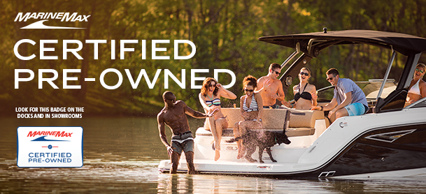 Group of people enjoying on a boat, surrounded by a lake with lush greenery. Text reads “MarineMax Certified Pre-Owned.” Fun, leisure, summer vibes.