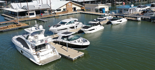 A marina with several white yachts docked on calm water.