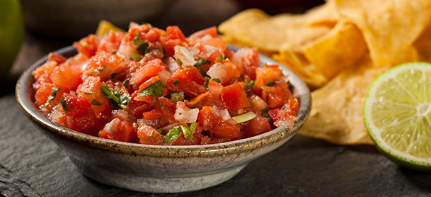 Salsa and chips with lime on a platter