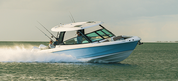 A sleek, white and blue motorboat speeds across the water, creating a foamy wake.