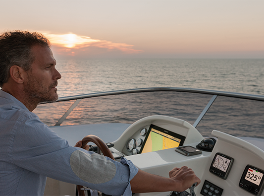 man driving a boat during sunset