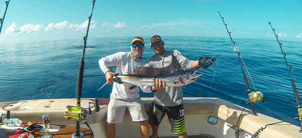 two guys holding fish on fishing boat