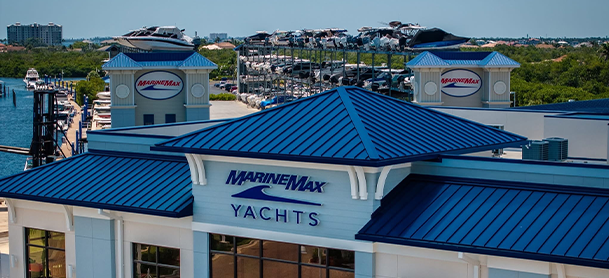 A marina with boats docked near MarineMax Fort Myers building featuring a blue roof.