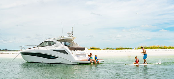 Galeon yacht anchored in water with family paddle boarding 