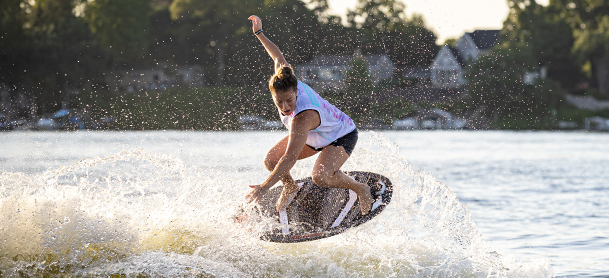 Surfer in mid-air performing a trick on a wave, with water droplets sparkling around.