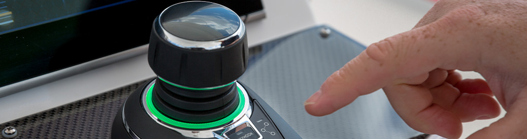 A hand pointing at a joystick on a boat