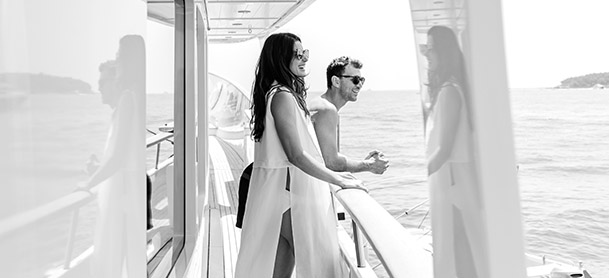 A man and woman standing on a yacht looking at the water