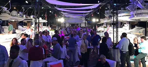 purple lights on at night during an outdoor boat show with several people