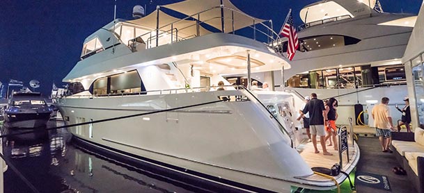people stepping on board a large boat at night at an outdoor boat show