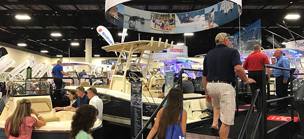 people walking up a set of stairs to look at boats at an indoor boat show