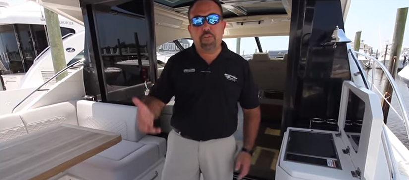male on aft deck of yacht pointing to features