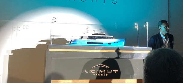 A model of the Azimut S10 in a glass case, being presented at the Cannes Yachting Festival in front of a crowd