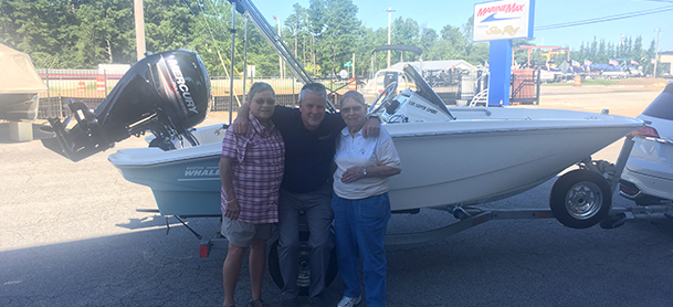Three people standing in front of a Bosotn Whaler boat at MarineMax Gulf Shores