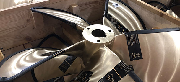 A gray metal engine propeller resting in a box in a factory